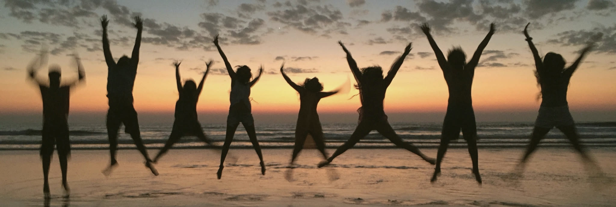 Travellers leaping against a sunset