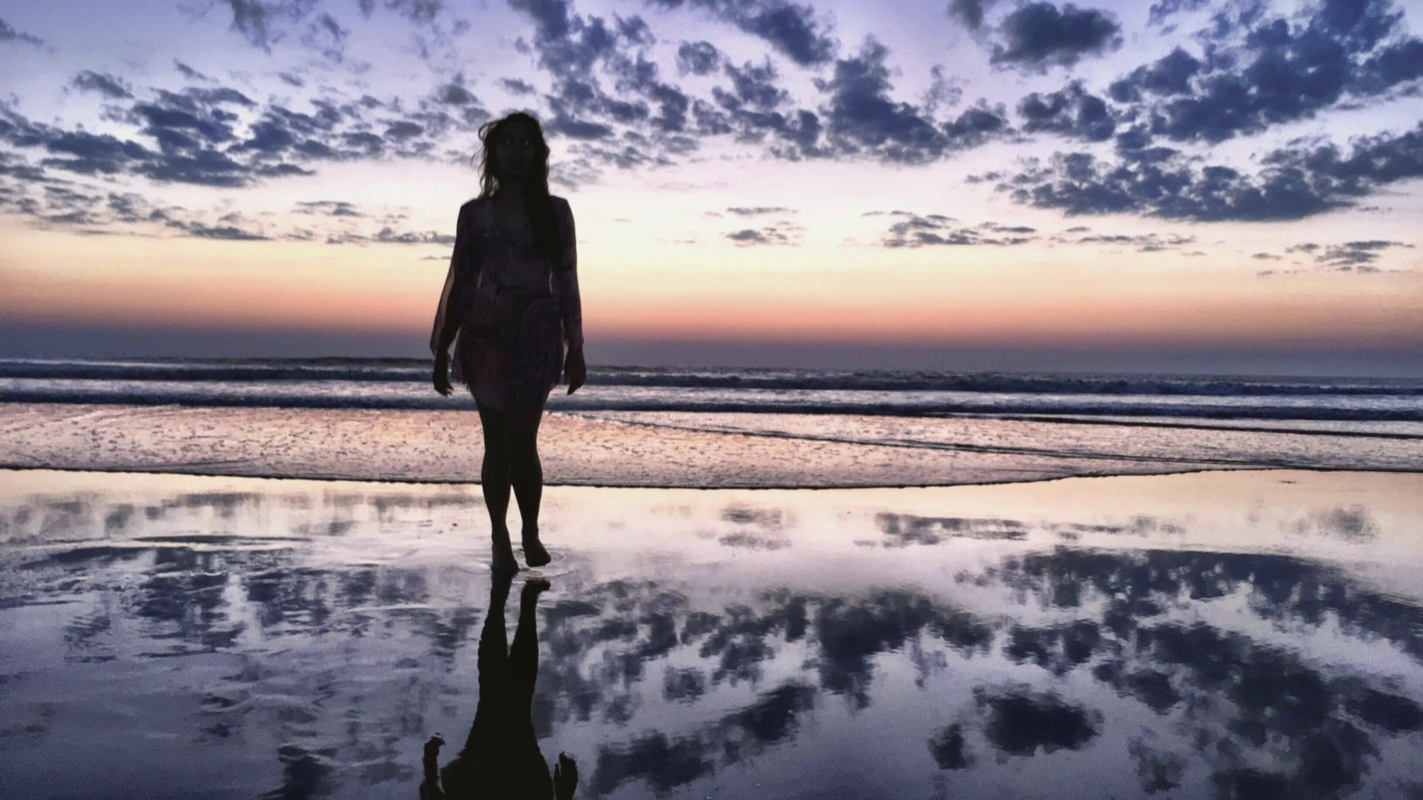 A traveller on a mirrored shore at dusk